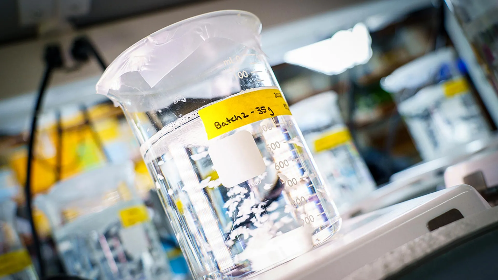 Intravenous fluid bag with measurement markings in a hospital background, yellow batch label reading 'Batch 2 - 35 g'