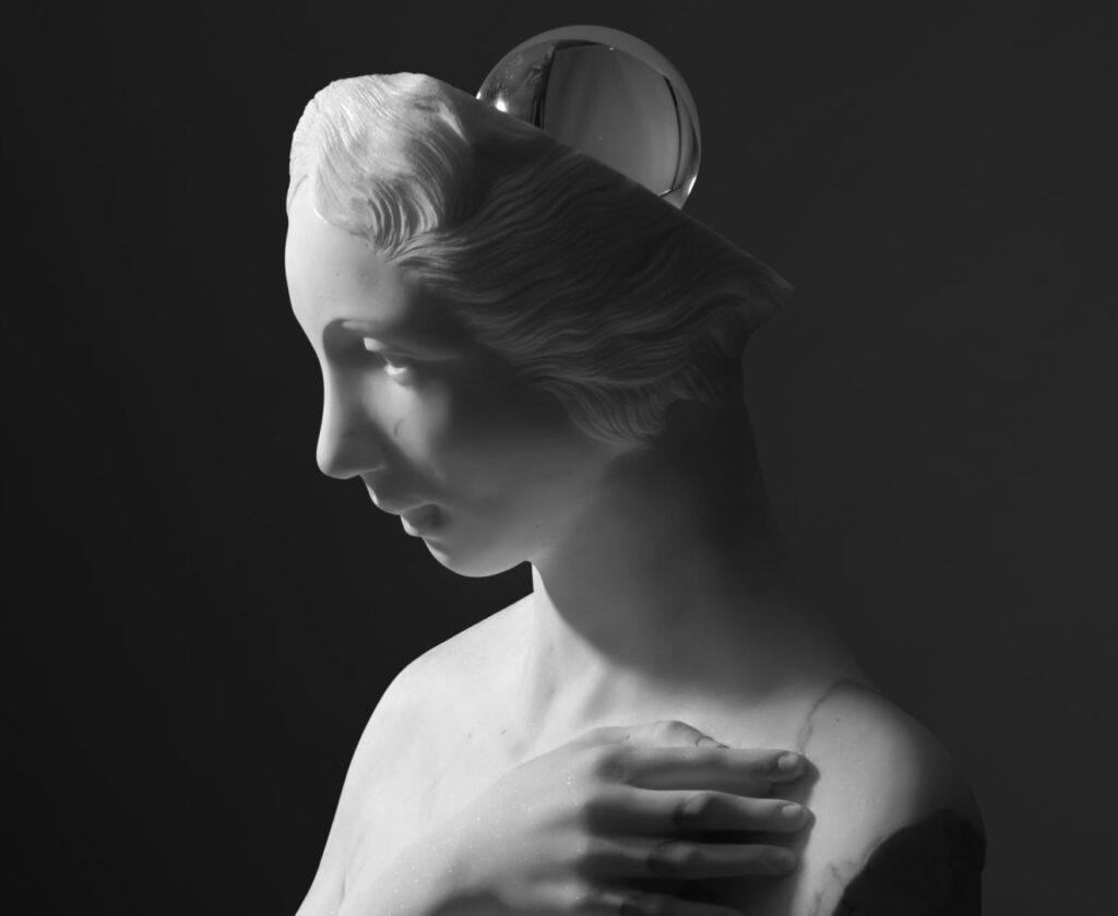 Gray statue of a woman with hair swept back, resting her hand on her chest against a dark background.