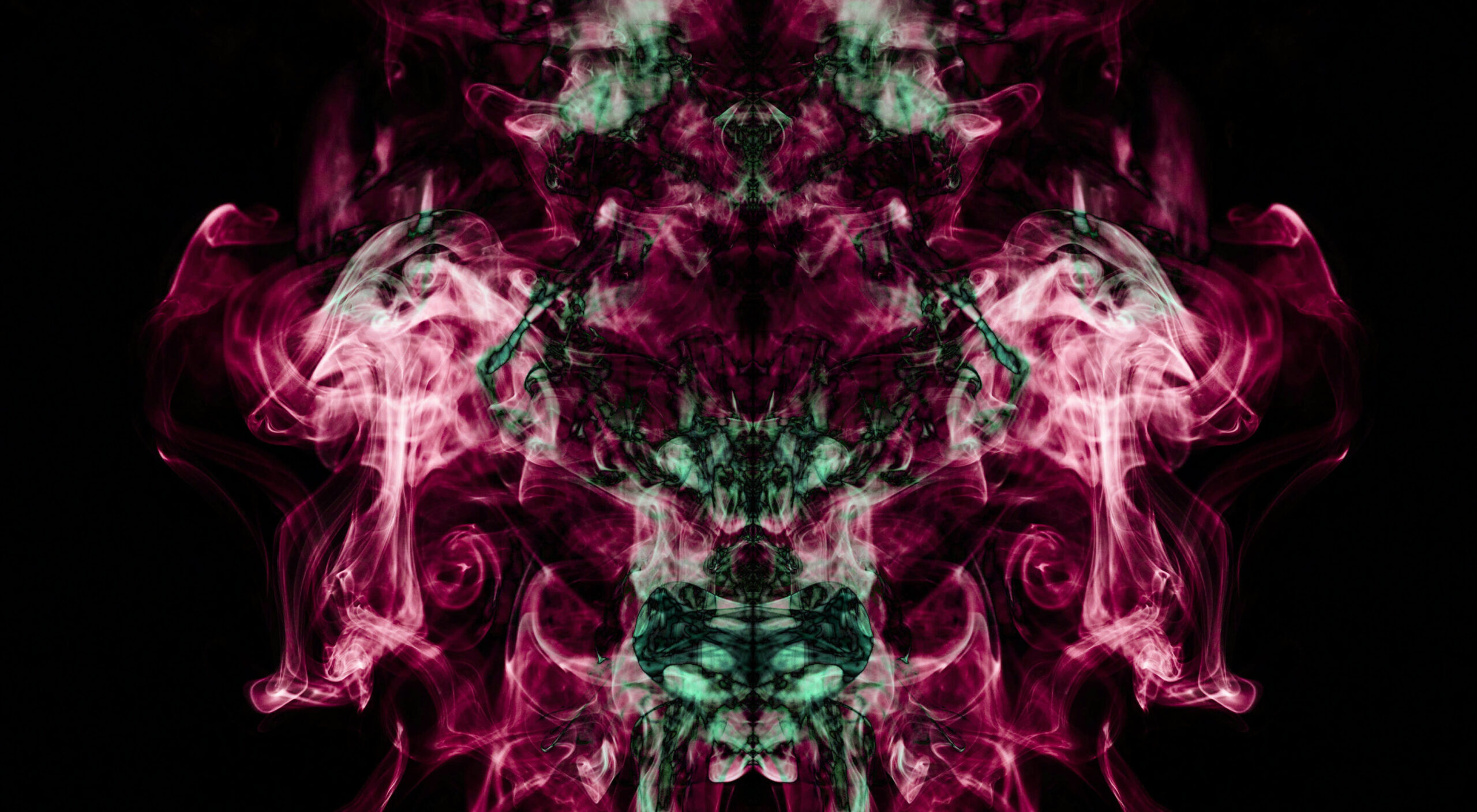 Symmetrical abstract smoke in magenta and green against a black background, forming a mirrored pattern.